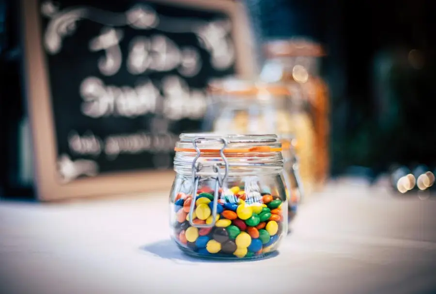 Frascos de vidrio con dulces de colores en un mostrador