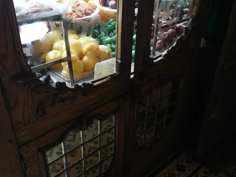 Interior de la dulcería: vitrinas de madera, dulces en exhibición y piso de mosaico