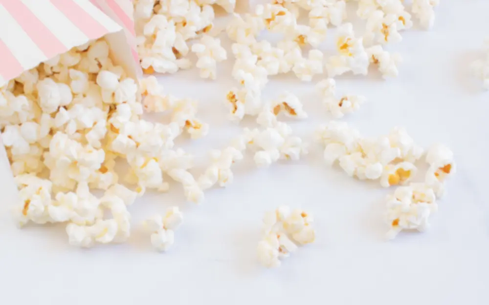 Palomitas servidas en conos de papel rosa sobre mármol